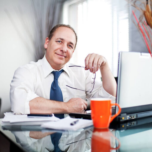 Male office worker smiling at desk to camera