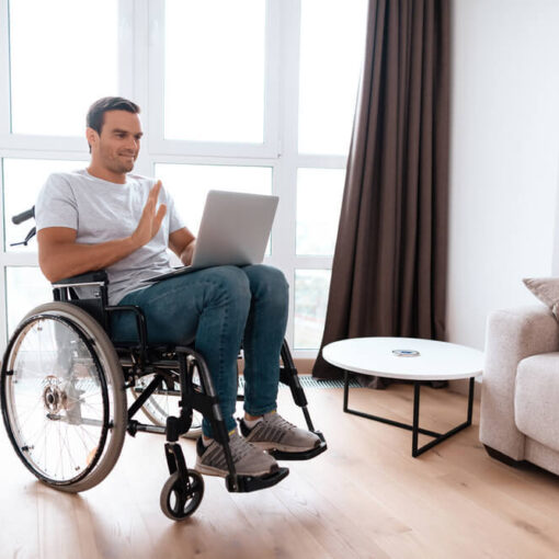Man in wheelchair at home on laptop