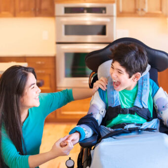 boy in wheelchair smiling at support worker
