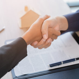 two hands shaking together over contract